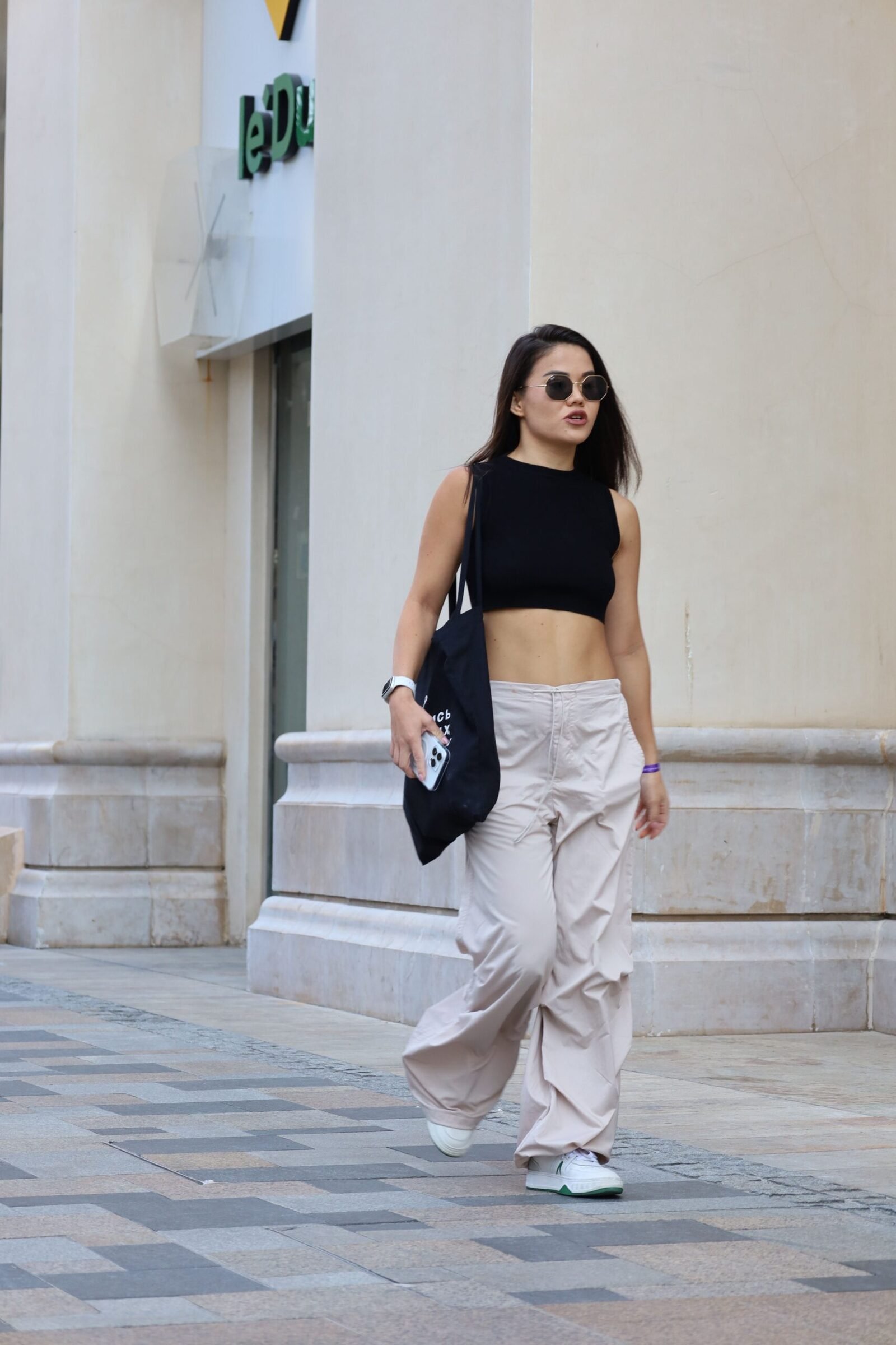 Balloon Pants Outfit Ideas 2026: How to Style the It Trousers 3 Woman in a black top and baggy wide-leg pants walking a sunny city street